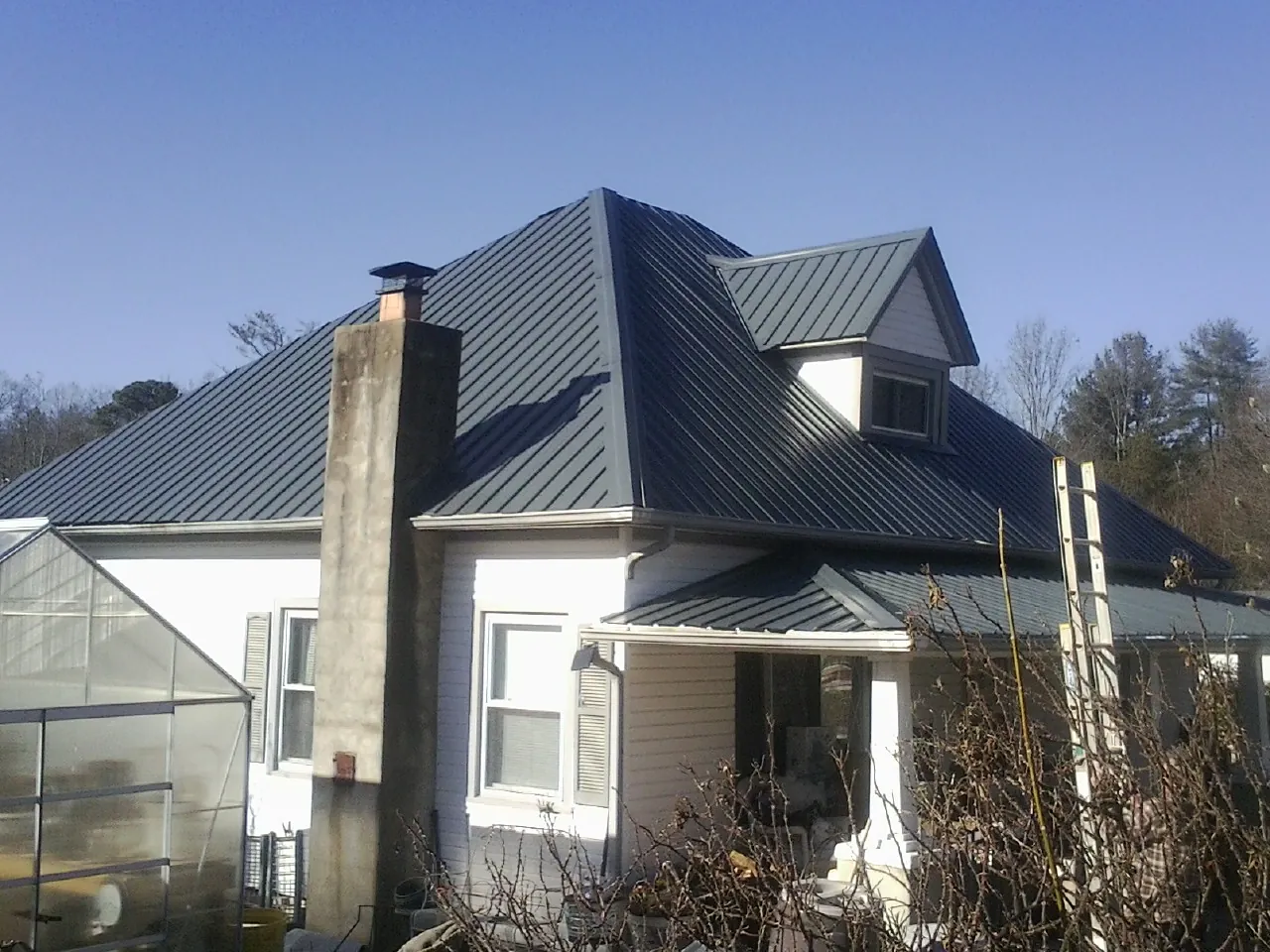 Dark blue standing seam metal roof on a white farmhouse with dormer — Slate & Tile Roof Repair by Roofing Brothers in Belchertown
