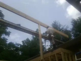 Carpenter setting a ridge beam over a new addition frame — Ice Dam Removal by Roofing Brothers in Belchertown