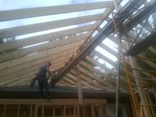 Rafters going up over a new addition with a worker on the wall in Belchertown