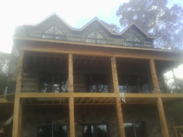 Dormers and porch framing on a large log home under construction — Roof Coating work by our crew in Belchertown