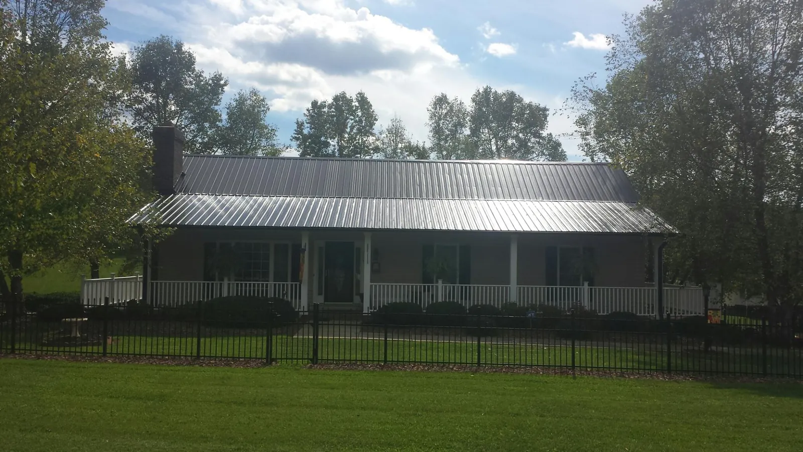 Gray metal roof on a brick ranch with a full width front porch — Gutter Guard Installation work by our crew in Belchertown