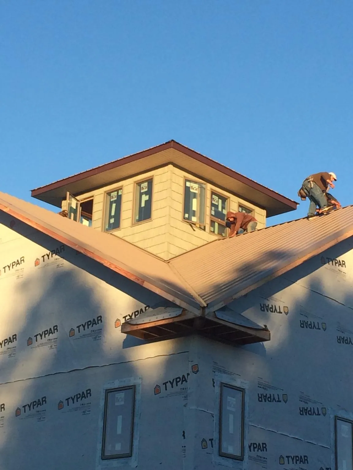 Roofers working around a rooftop cupola on a new metal roof at sunset — Roof Waterproofing in Belchertown by Roofing Brothers